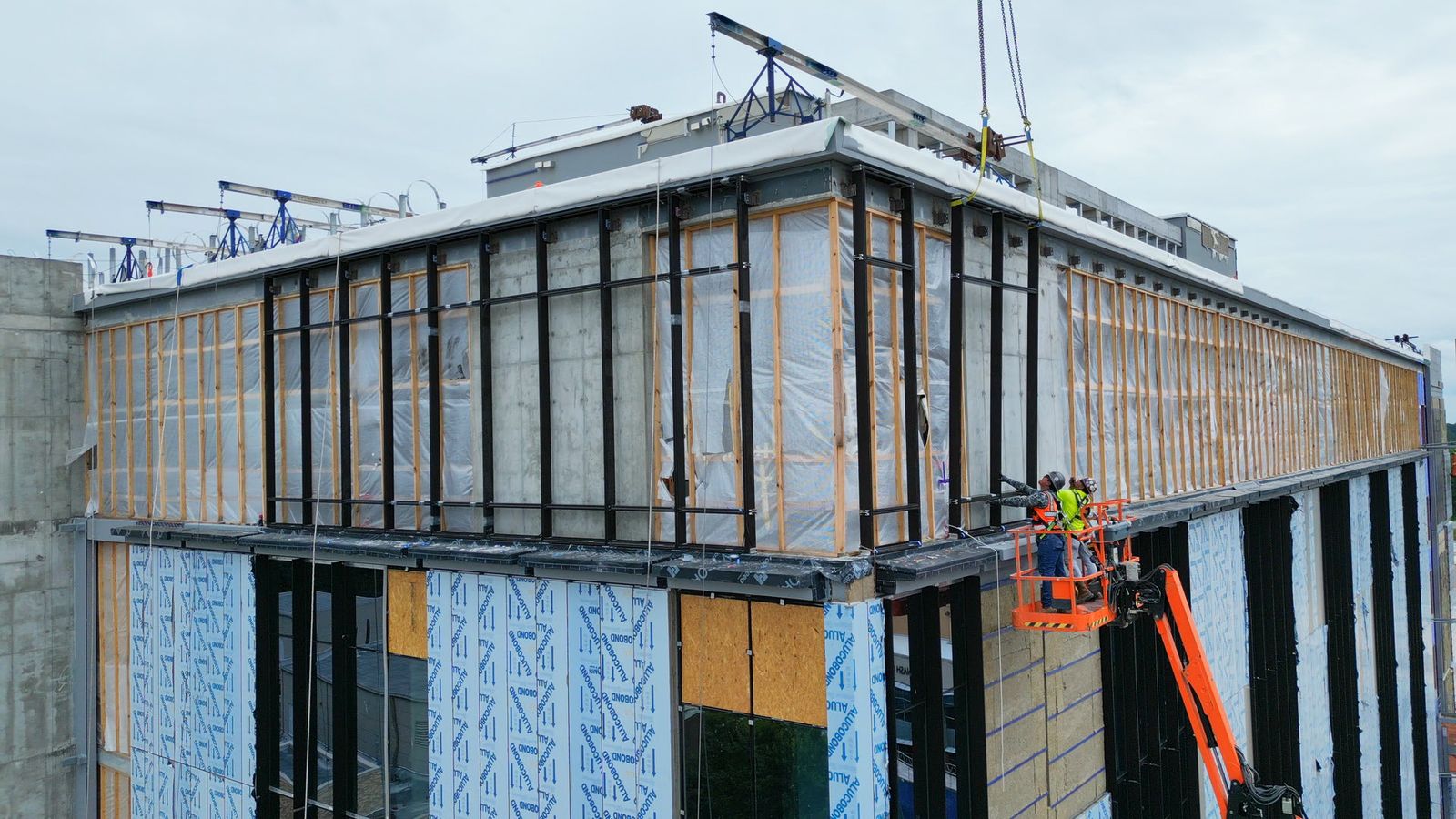 Brinn Glass installers setting curtain wall frames from a lift